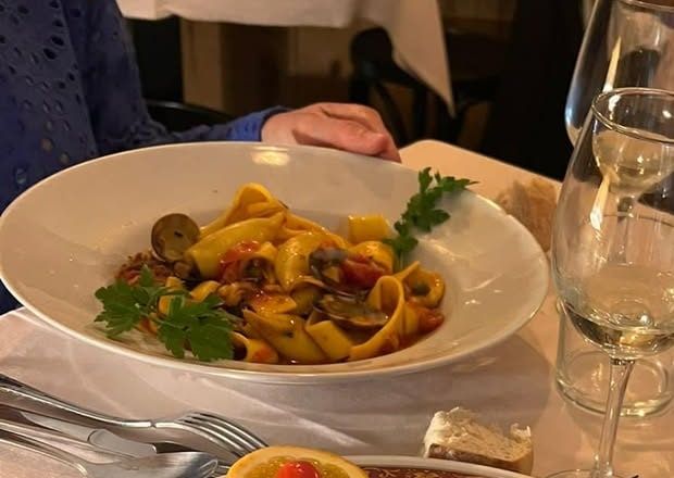 Pappardelle with clams and tomato in a white bowl