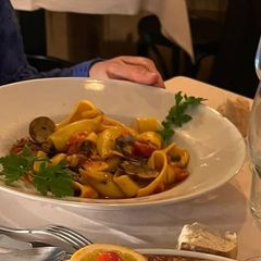 Pappardelle with clams and tomato in a white bowl