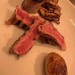 Rare sliced beef with a marrow bone, mushrooms and a roast potato